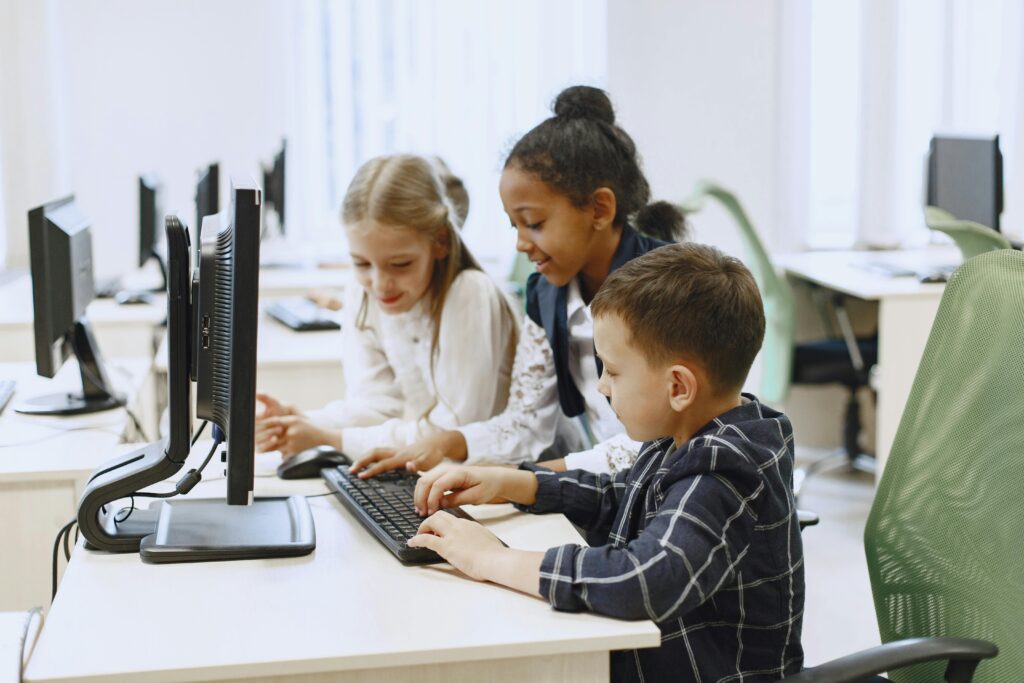 Children in a computer lab learning and collaborating on projects together.